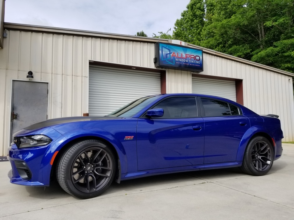 Professional auto window tinting on blue sedan